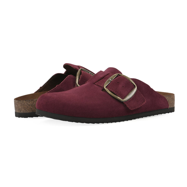 Angle view of a pair of burgundy suede backless clogs with large adjustable buckle and a black sole