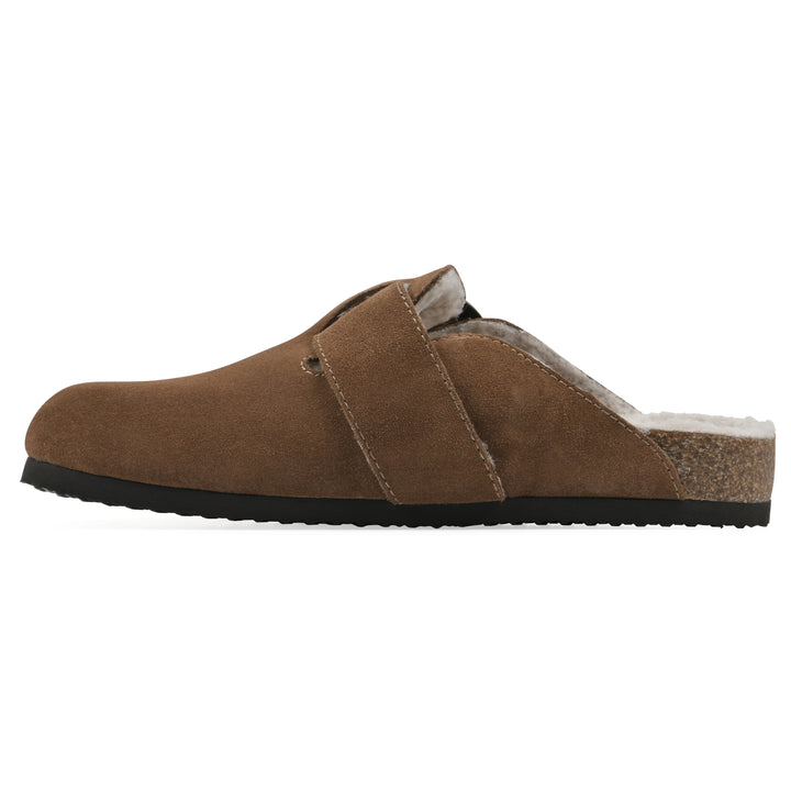 Side view of a chestnut suede backless clog with cream, faux fur lining, a large adjustable buckle, and a black sole