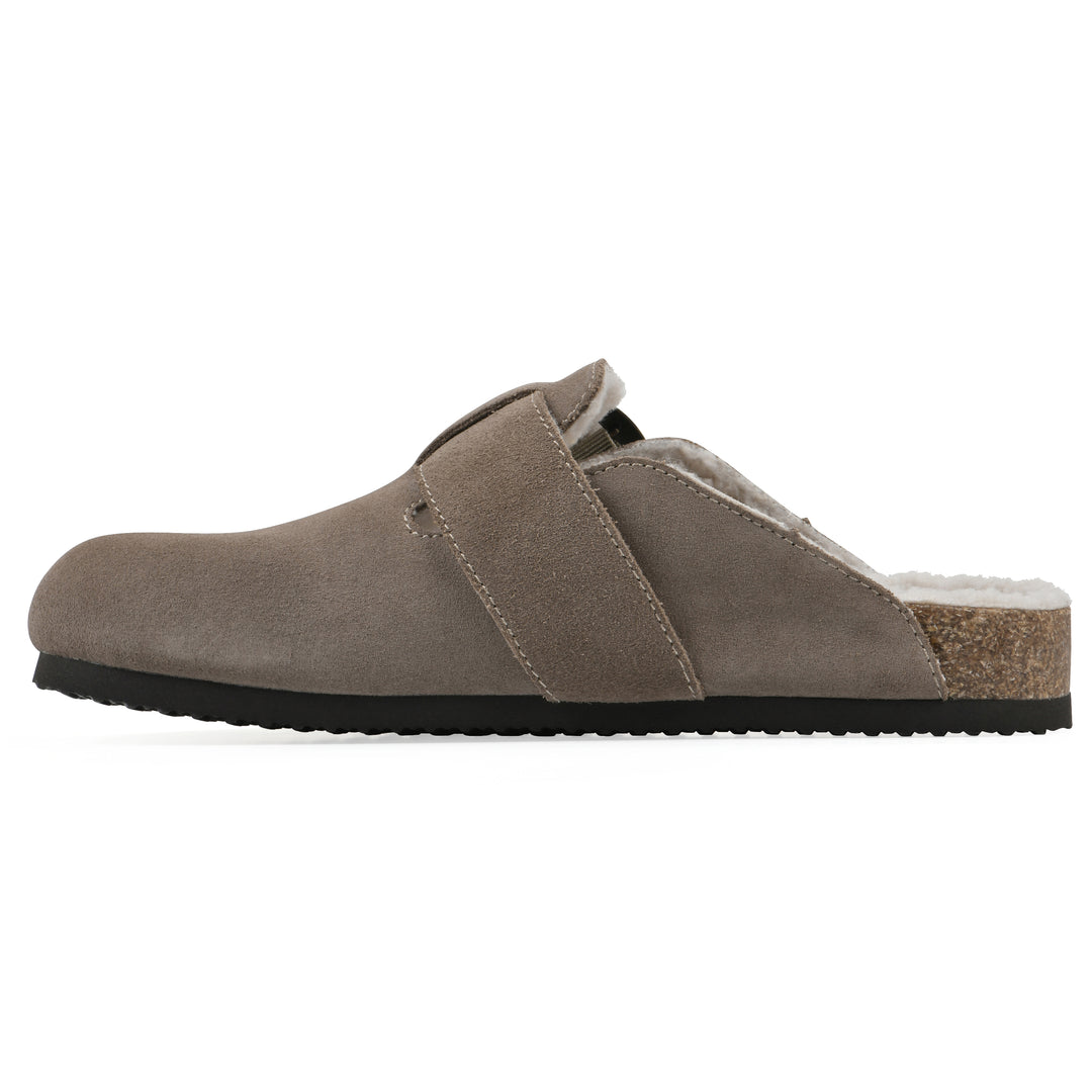 Side view of a taupe suede backless clog with cream, faux fur lining, a large adjustable buckle, and a black sole