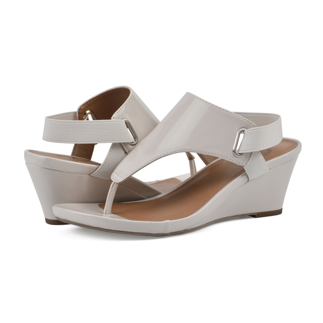 Angle view of a pair of eggshell patent thong wedge sandals with a wrapped heel, elastic ankle strap, and eggshell sole