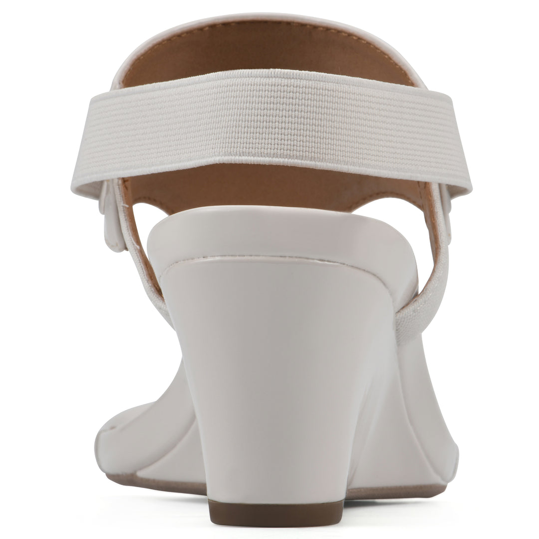 Rear view of an eggshell patent thong wedge sandal with a wrapped heel, elastic ankle strap, and eggshell sole