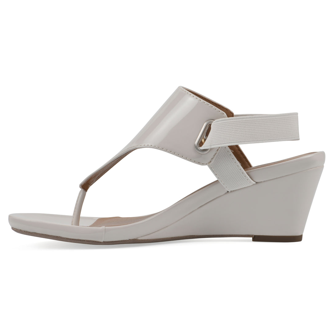 Side view of an eggshell patent thong wedge sandal with a wrapped heel, elastic ankle strap, and eggshell sole