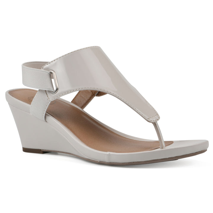 Angle view of an eggshell patent thong wedge sandal with a wrapped heel, elastic ankle strap, and eggshell sole