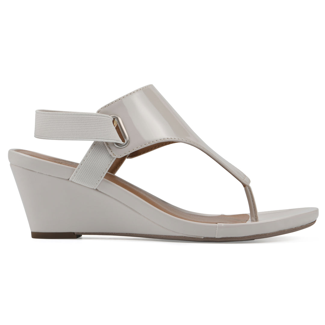 Side view of an eggshell patent thong wedge sandal with a wrapped heel, elastic ankle strap, and eggshell sole
