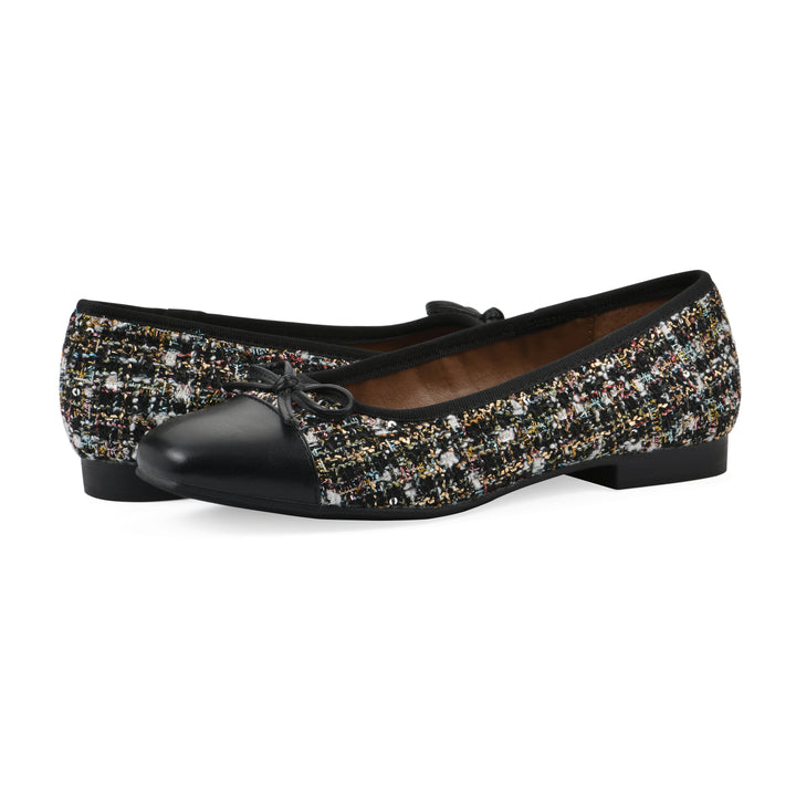 Angle view of a pair of black boucle fabric flats with small, centered black bow, a smooth black patent toe cap, and a black sole