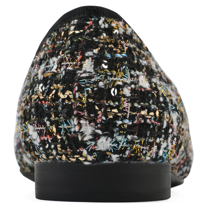 Rear view of a black boucle fabric flat with small, centered black bow, a smooth black patent toe cap, and a black sole
