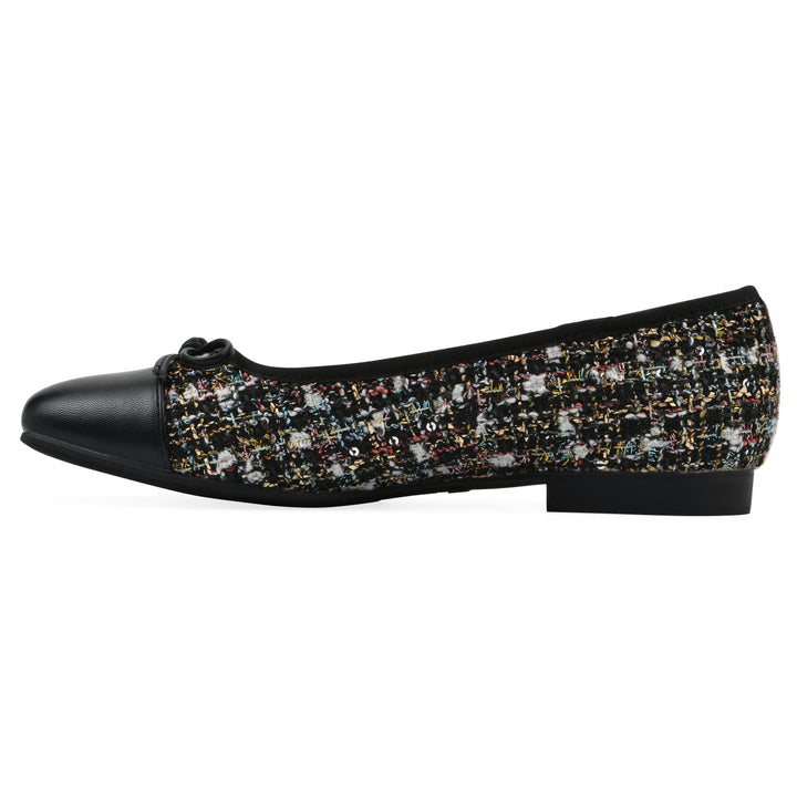 Side view of a black boucle fabric flat with small, centered black bow, a smooth black patent toe cap, and a black sole