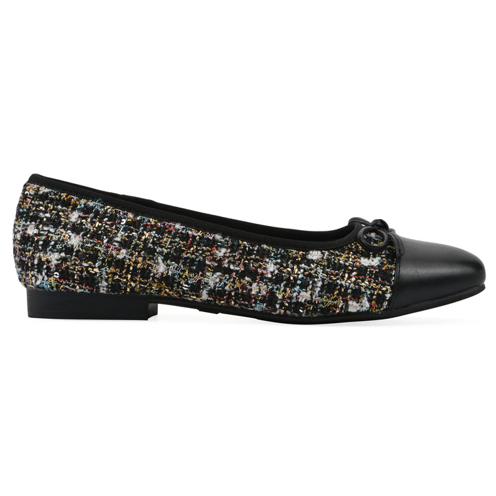 Side view of a black boucle fabric flat with small, centered black bow, a smooth black patent toe cap, and a black sole