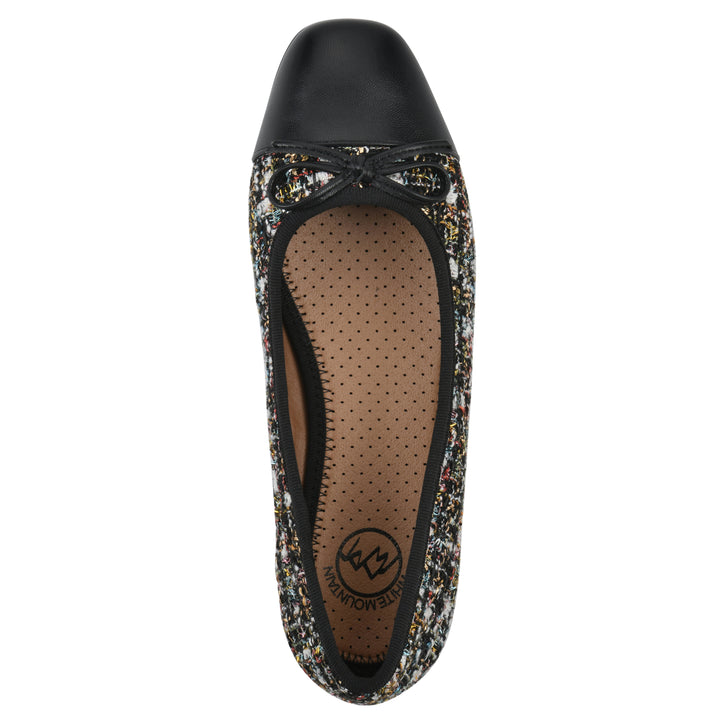 Top view of a black boucle fabric flat with small, centered black bow, a smooth black patent toe cap, and a black sole