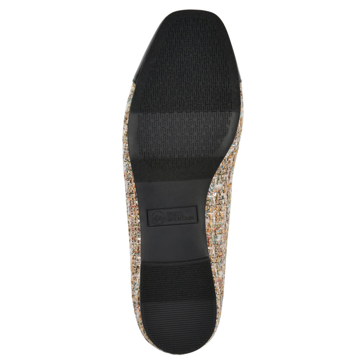 Sole view of a beige boucle fabric flat with small, centered black bow, a smooth black patent toe cap, and a black sole