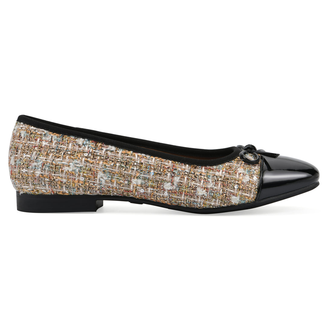 Side view of a beige boucle fabric flat with small, centered black bow, a smooth black patent toe cap, and a black sole