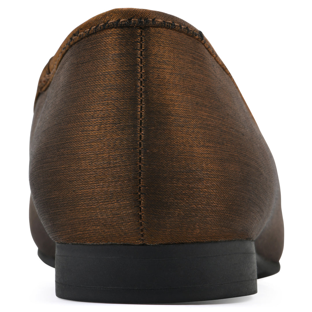 Rear view of a bronze shimmer fabric flat with small, centered black bow and a black sole