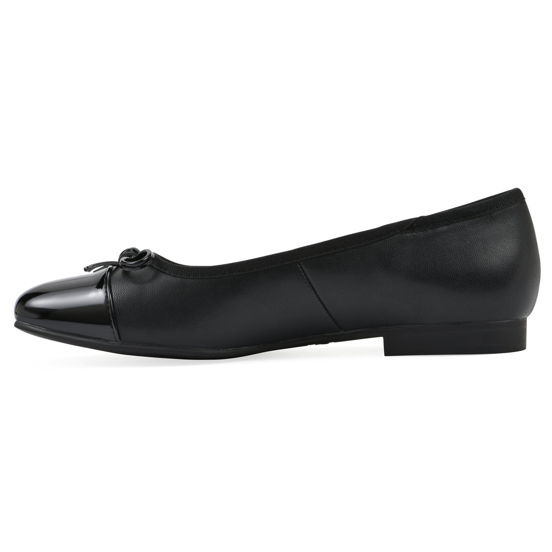 Side view of a black faux leather flat with small, centered black bow, a smooth black patent toe cap, and a black sole