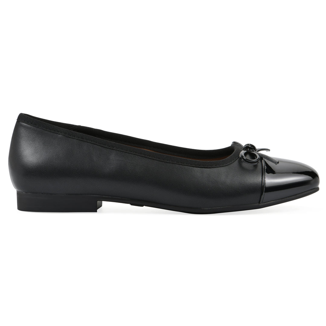 Side view of a black faux leather flat with small, centered black bow, a smooth black patent toe cap, and a black sole