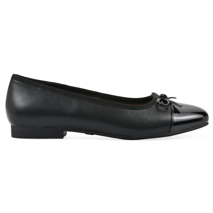 Side view of a black faux leather flat with small, centered black bow, a smooth black patent toe cap, and a black sole