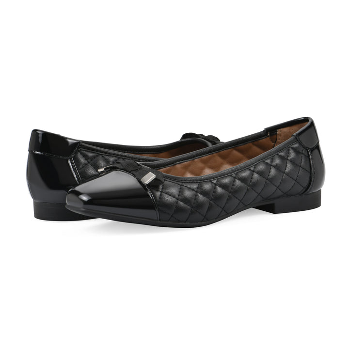 Angle view of a pair of black quilted pattern flats with smooth patent toe cap, small, centered bow and a black sole