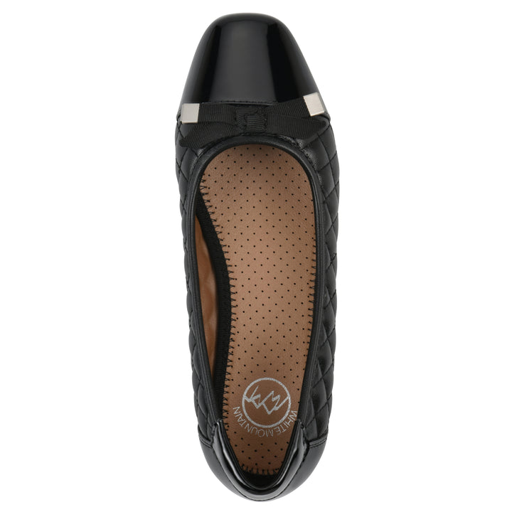 Top view of a black quilted pattern flat with smooth patent toe cap, small, centered bow and a black sole