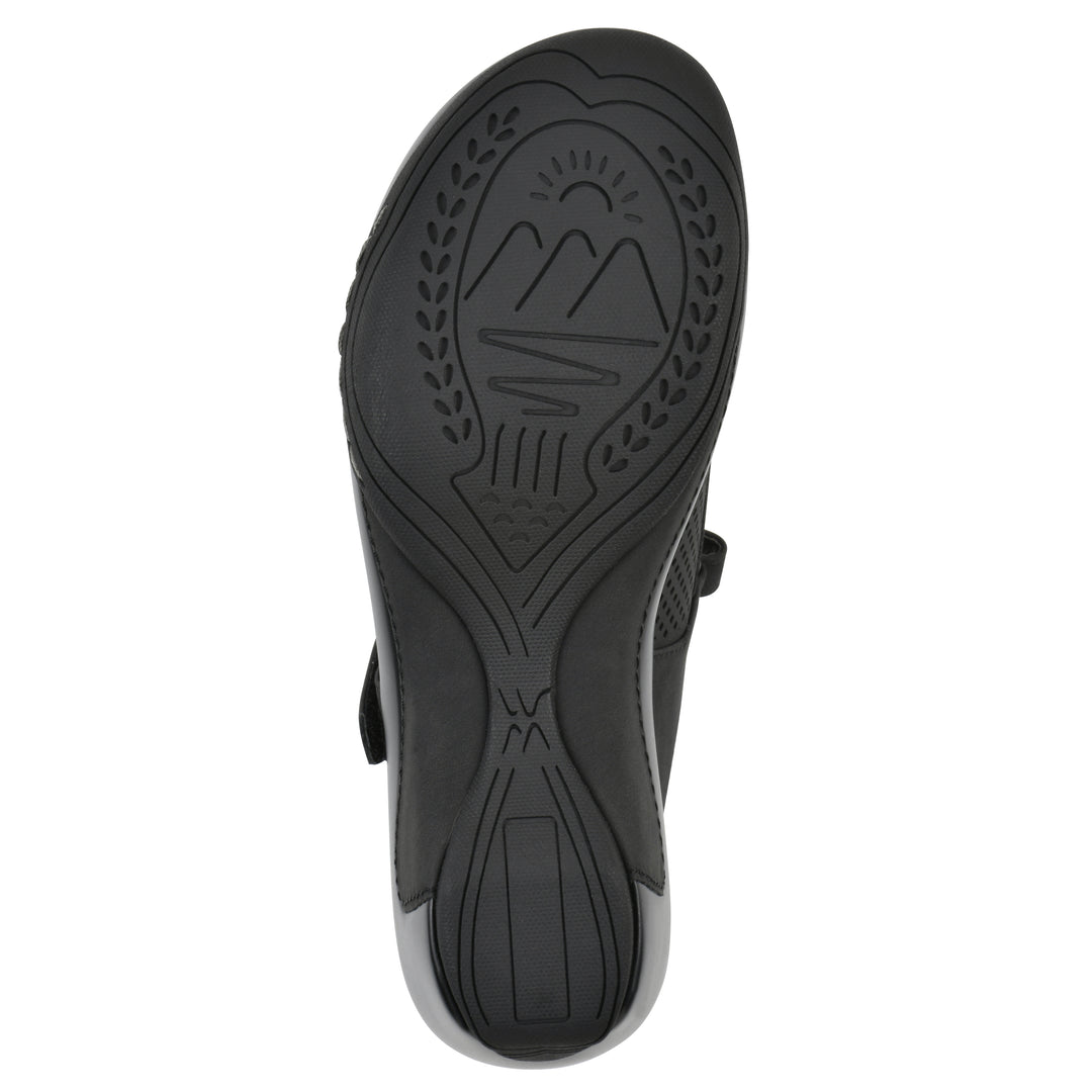 Sole view of a black colored clog with a closed toe and adjustable strap, featuring a perforated diamond design and a low heel.