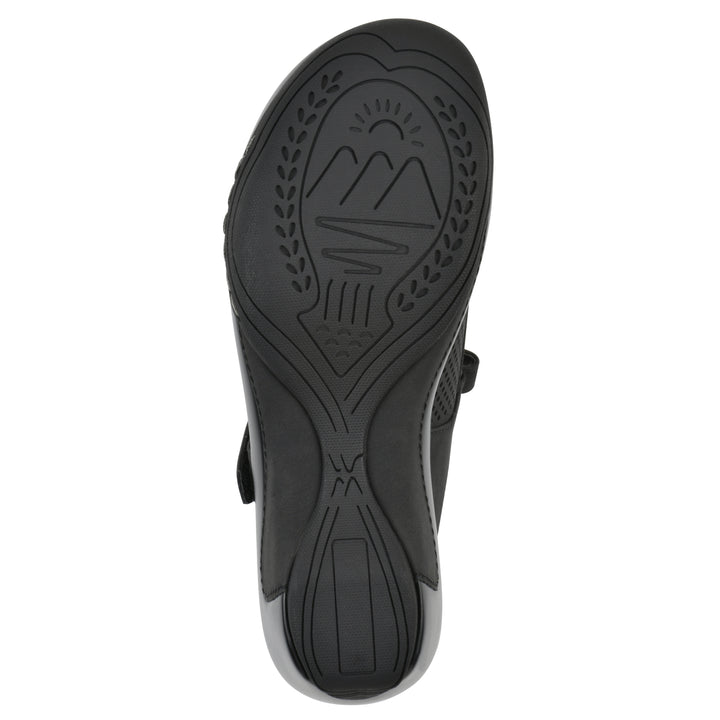 Sole view of a black colored clog with a closed toe and adjustable strap, featuring a perforated diamond design and a low heel.
