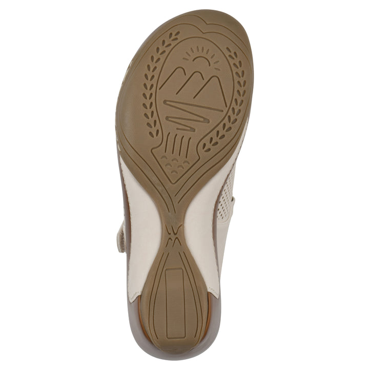 Sole view of a egg shell colored clog with a closed toe and adjustable strap, featuring a perforated diamond design and a low heel.