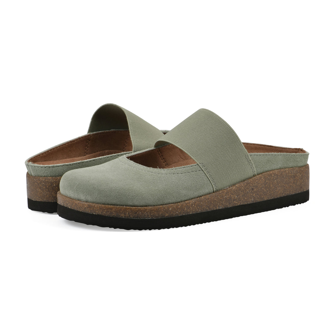 Angle view of a pair of sage suede backless clogs with Mary Jane style center strap and a brown sole with black bottom