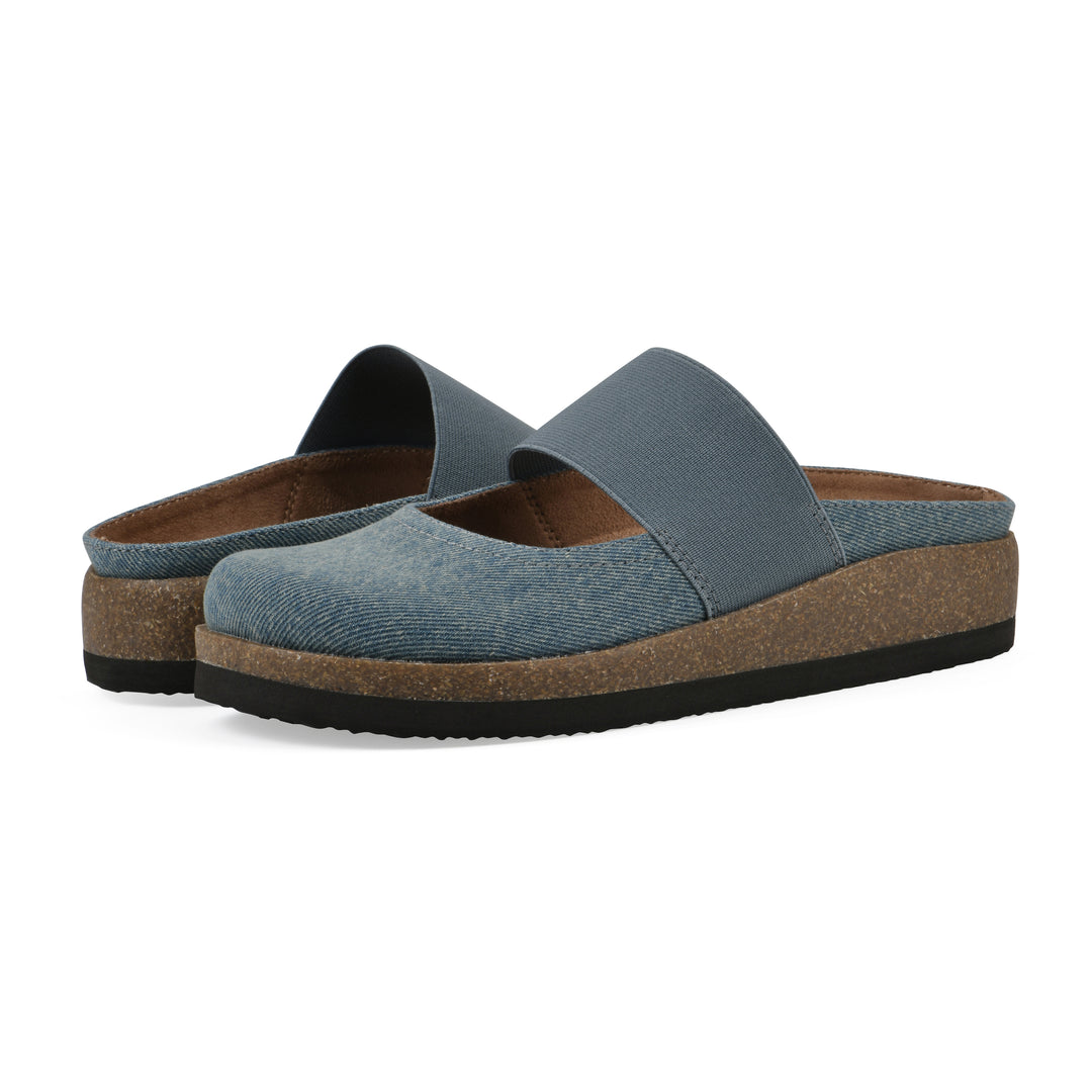 Angle view of a pair of denim backless clogs with Mary Jane style center strap and a brown sole with black bottom