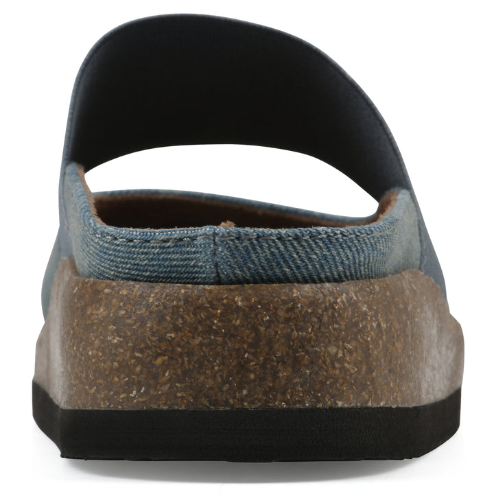 Rear view of a denim backless clog with Mary Jane style center strap and a brown sole with black bottom