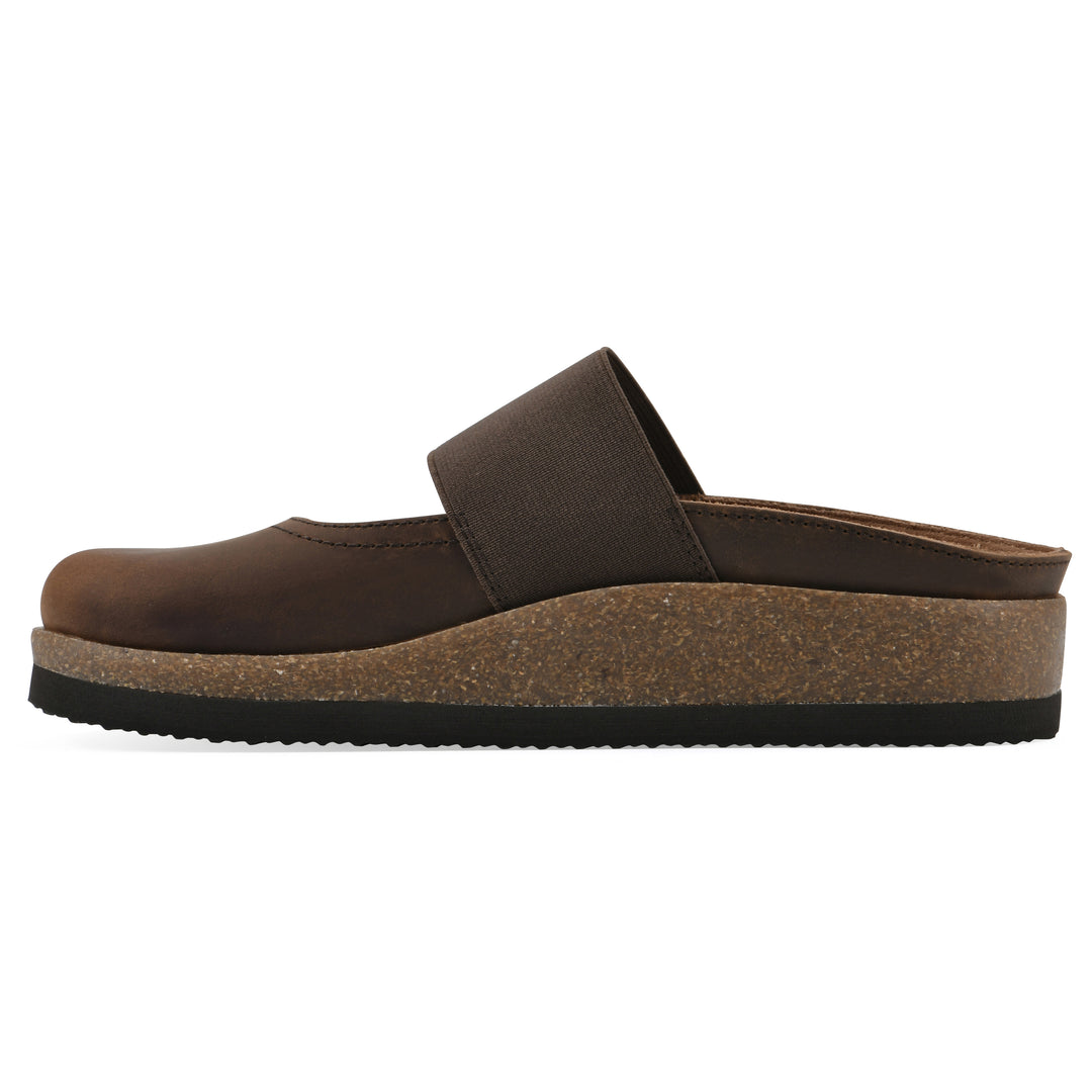 Side view of a brown leather backless clog with Mary Jane style center strap and a brown sole with black bottom