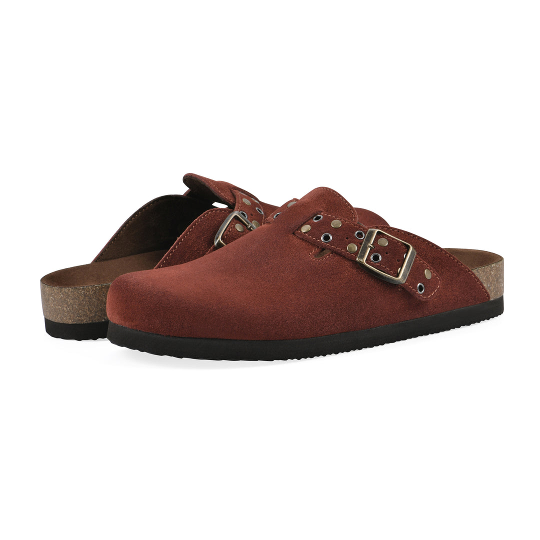 Angle view of a pair of rust suede backless clogs with an adjustable buckle strap with stud and eyelet detailing and a black sole