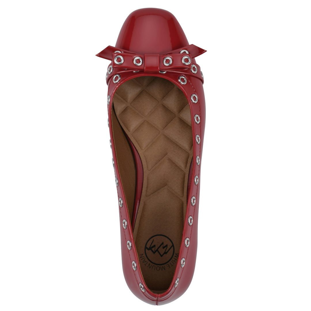Top view of a red patent flat with small, centered bow, silver metal grommet lining and a black sole