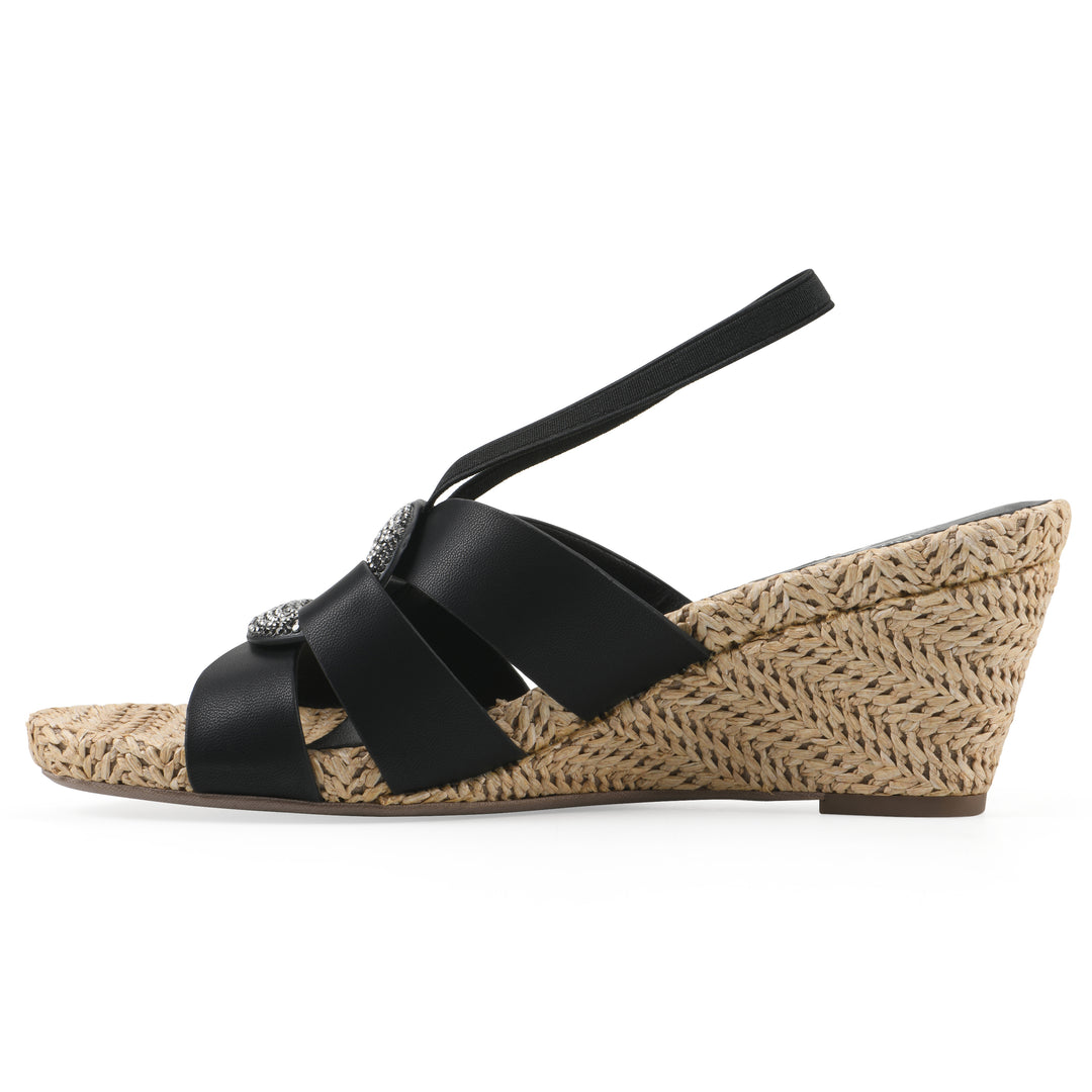 Side view of a black wedge sandal with elastic heel strap, woven raffia sole and a centered, sequin applique