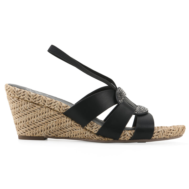 Side view of a black wedge sandal with elastic heel strap, woven raffia sole and a centered, sequin applique
