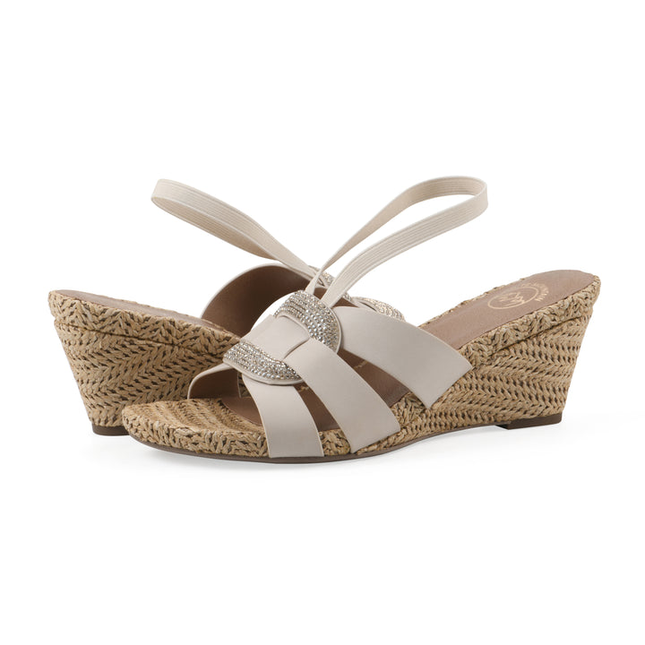 Angle view of a pair of cream wedge sandals with elastic heel strap, woven raffia sole and a centered, sequin applique