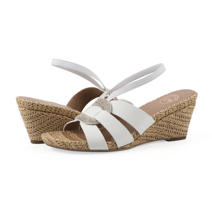 Angle view of a pair of white wedge sandals with elastic heel strap, woven raffia sole and a centered, sequin applique