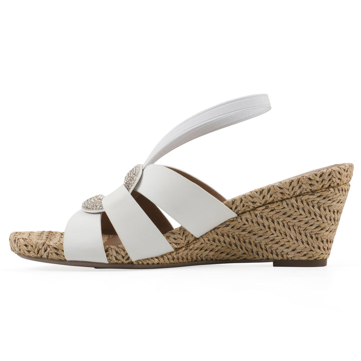 Side view of a white wedge sandal with elastic heel strap, woven raffia sole and a centered, sequin applique