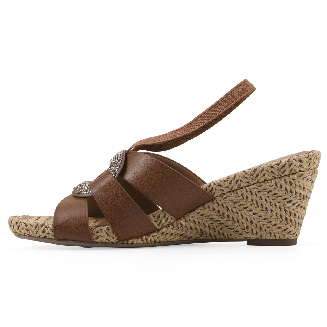 Side view of a brown wedge sandal with elastic heel strap, woven raffia sole and a centered, sequin applique