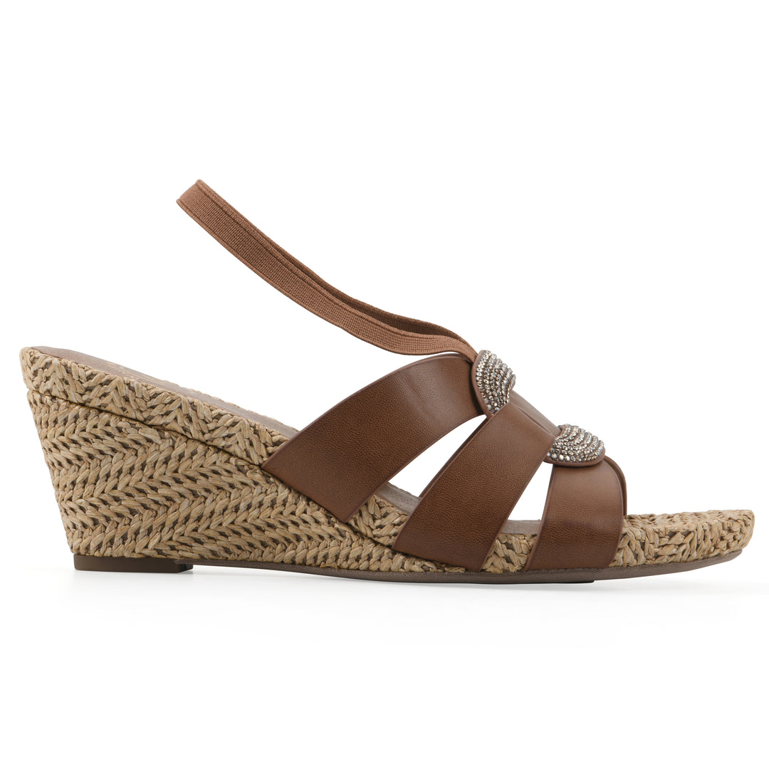 Side view of a brown wedge sandal with elastic heel strap, woven raffia sole and a centered, sequin applique