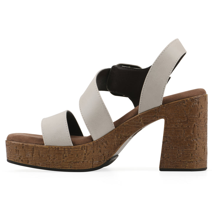 Side view of a white platform sandal with ankle buckle and a brown, faux cork sole