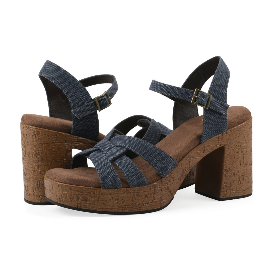 Angle view of a pair of denim blue fabric platform sandals with buckle style ankle strap and a brown molded cork sole