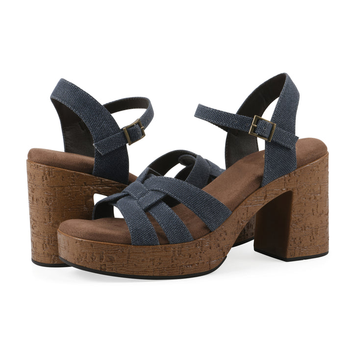 Angle view of a pair of denim blue fabric platform sandals with buckle style ankle strap and a brown molded cork sole