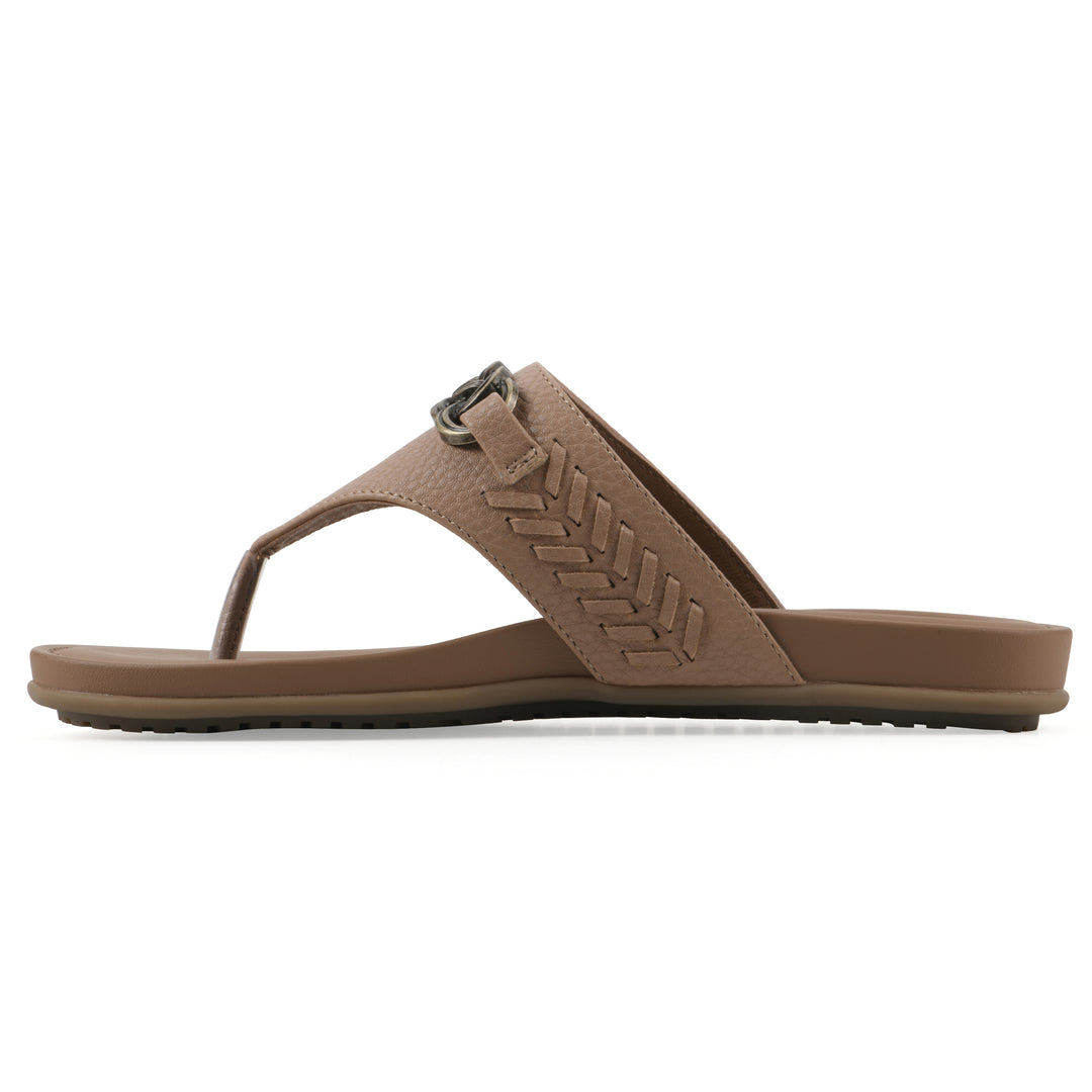 Side view of a tan thong sandal with metal embellishment and a brown sole