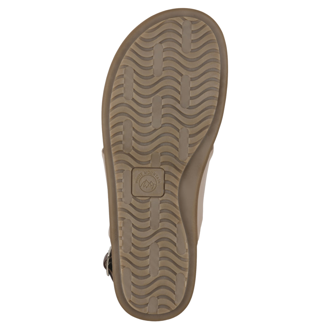 Sole view of a tan thong sandal with a centered metallic ring, adjustable heel strap, and beige sole