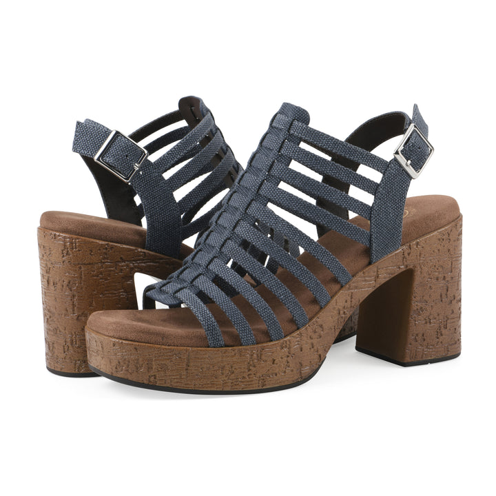 Angle view of a pair of denim gladiator platform sandals with adjustable ankle buckle and cork style heel